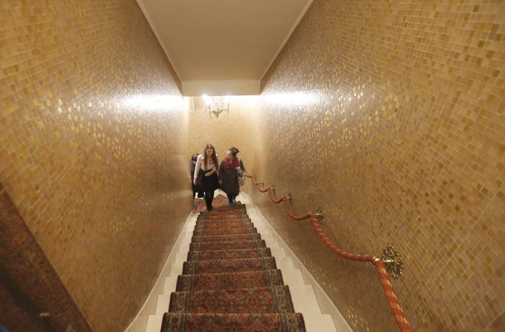 Román idegenvezető és kínai turista megy fel a lépcsőn a borpincének helyet adó alagsorból